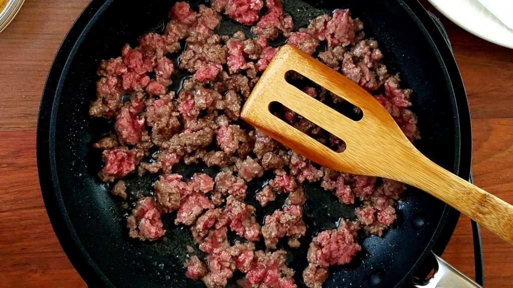 Ground beef sizzling in  a pan for our cheeseburger pizza