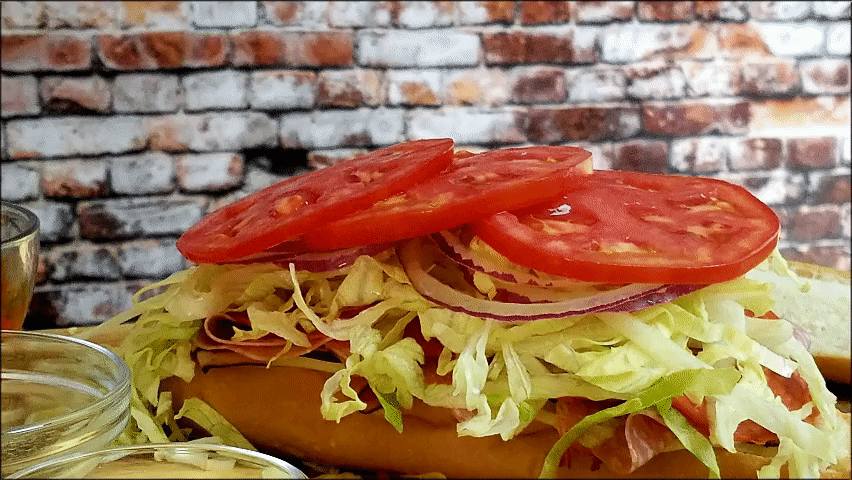 Sub roll topped mikes way with lettuce, onions, tomatoes and the juice