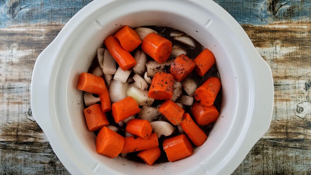 carrots and onions in a slow cooker with sauce