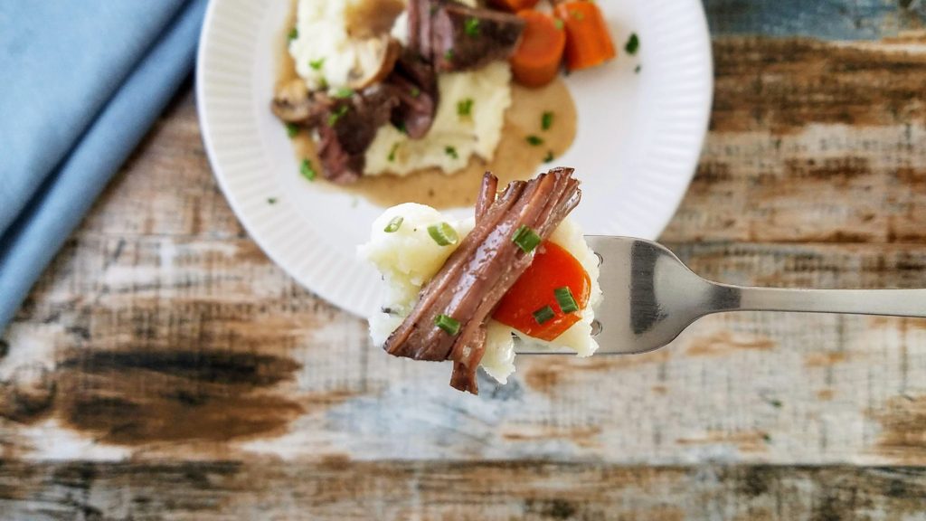 Bite of pot roast with mashed potatoes on a fork
