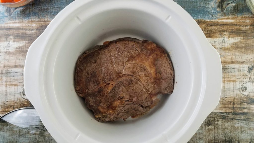 chuck roast placed in the bottom of the slow cooker